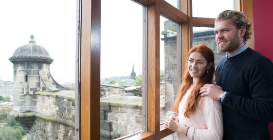 Couple standing at window with view of castle