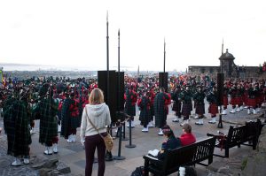 A visitor standing behind a large crowd of pipers getting ready to play at the Tattoo
