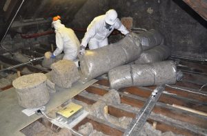 Two man in hazard suits handling sheepwool insulation in the attic of Edinburgh Castle