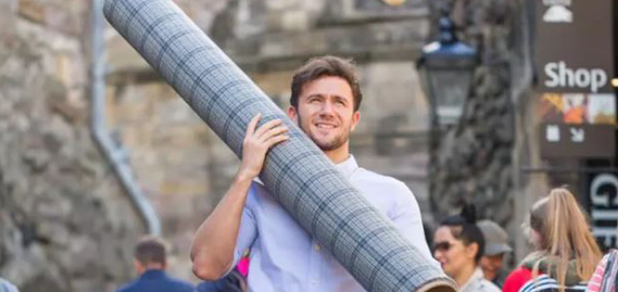 man carrying a role of tweed fabric