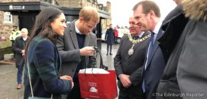 Prince Harry and Meghan Markle visiting Edinburgh Castle. Harry is holidng and Edinburgh Castle gift bag containing a gift for the happy couple