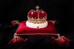 A crown sits of a red velvet cushion