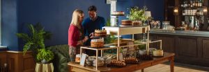 A man and a women browse a table laden with cakes and other treats