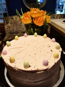 A cake with yellow icing and chocolate egg decoration