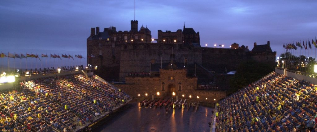 View of the Castle Esplanade by night with a military band marking in formation lit up by coloured lights