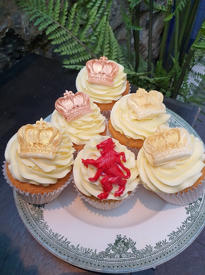 A plate of cupcakes decorated with iced crowns and dragons 