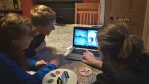 A woman and two children look at a laptop with a 3D model of Edinburgh Castle on its screen. Learning at home.