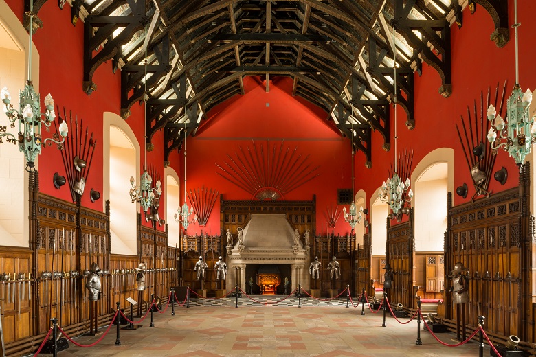 The Great Hall in Edinburgh Castle. It has an impressive timber ceiling with red walls decorated with weapons and suits of armour