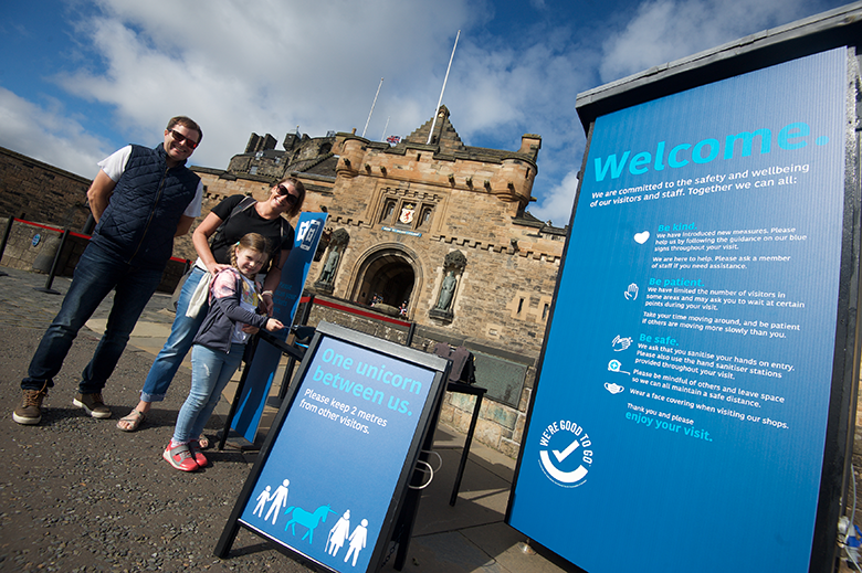 a family arrives at the entrance to Edinburgh Castle, where Covid safety measures and messaging are in place