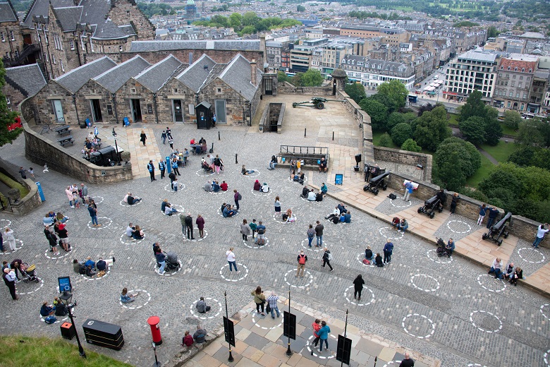 Visitors to Edinburgh Castle waiting to see the firing of the One O'Clock Gun. Each group is standing in a white circle which has been painted on the ground to ensure they are at least two metres apart