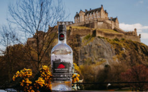 bottle of gin with a castle on a hill behind it