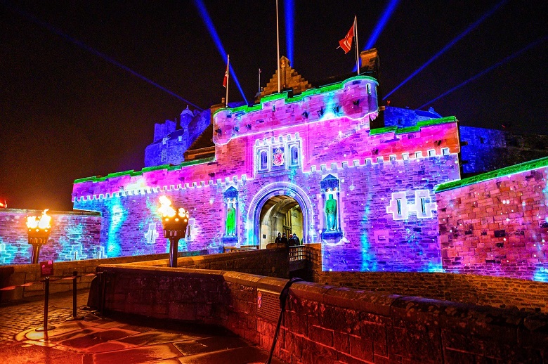 The main entrance to Edinburgh Castle spectacularly illuminated with colourful lasers and projections