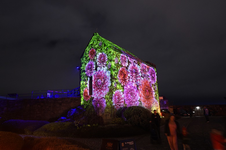 Colourful projections on the side of a small stone chapel in Edinburgh Castle