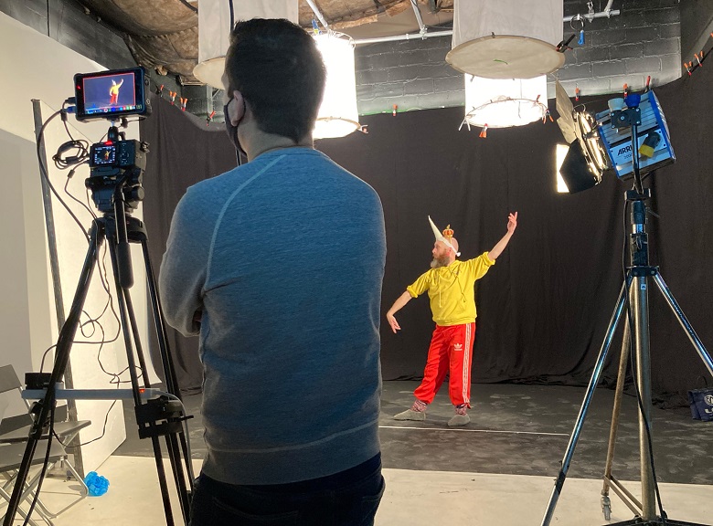 A behind the scenes photo of a man wearing a unicorn horn performing a dance for use in an animation 