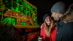 Two people smiling at each other standing in front of a light installation at Edinburgh Castle of Light.