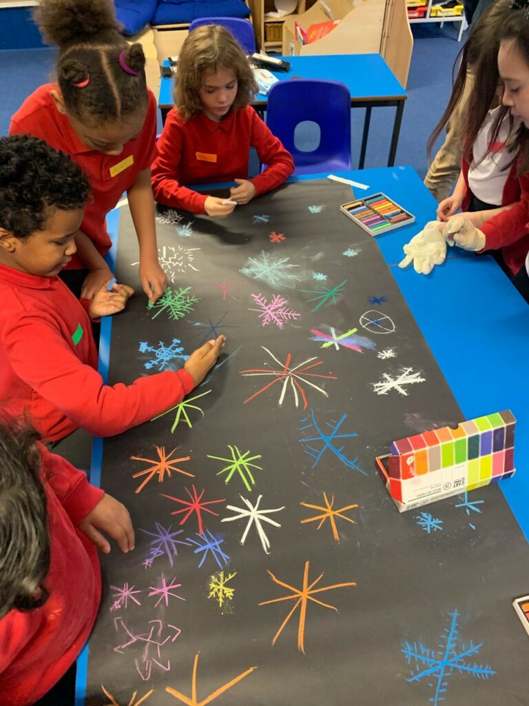 A group of young people drawing scenes from Edinburgh Castle of Light with chalk on black cardboard. 