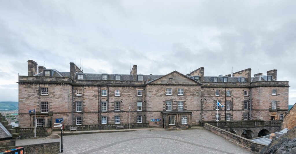 A large sandstone building with many windows. It looks bit like a prison. It's the New Barracks at Edinburgh Castle