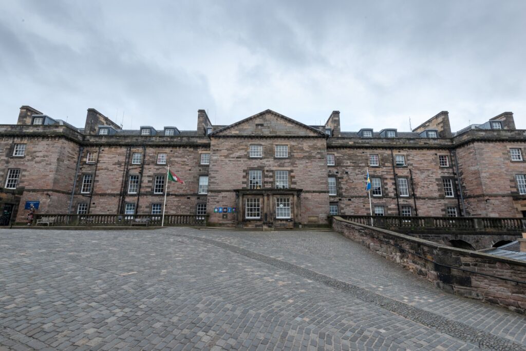 Ornate old building with a courtyard outside it under a grey sky.