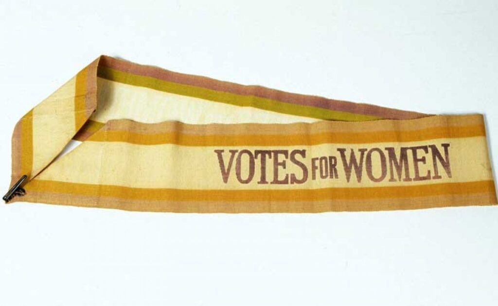 'Votes for Women' sash against a white background.
